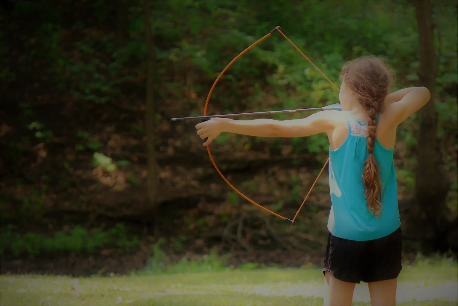 A young learner practicing archery outdoors
